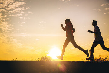 Silhouette of young couple running together on road. Couple, fit runners fitness runners during...