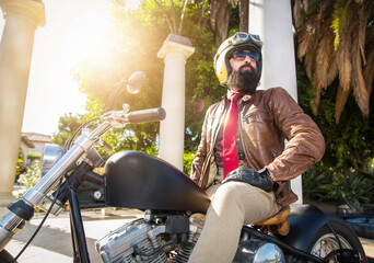 Close up of a man with a beard on a motorcycle wearing a gold helmet