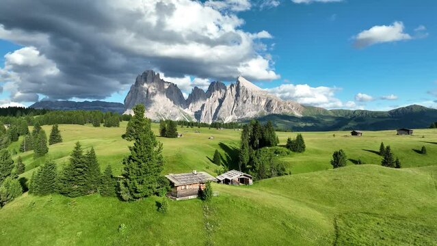 Aerial view of Seiser Alm valley with traditional wooden mountain huts in Dolomites Italy . Morning drone shot of idyllic Alpe di Suisi blooming meadow in South Tyrol