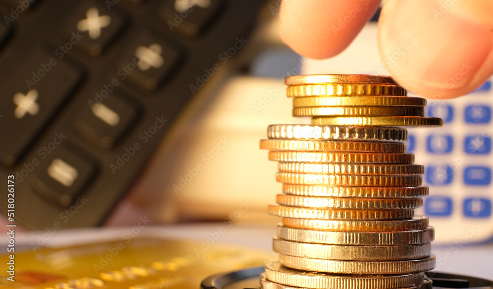 Wall mural Saving money and business growth concept with a stack of coins on a table, as well as a finance and investment concept.