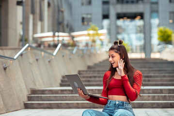 Woman on the street using laptop. Communicates via video link