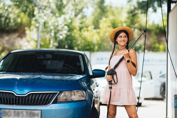 Naklejka premium Woman with high pressure hose at car wash