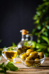 Green olives fruits in olive oil on wooden table
