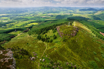 Fototapeta na wymiar Tall white Catholic cross on top of Devils bit mountain in county Tipperary, Ireland. Aerial view. Beautiful landscape with green fields and forests in the background. Irish landscape.