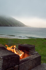 Fire burning in bonfire. Stunning Keem beach in the background. Blue ocean and sandy beach. Travel...