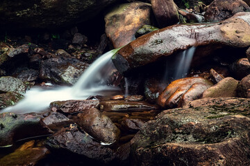 Water running through brown color rocks. Stunning nature scene. Motion blur of water. Calm and peaceful mood.