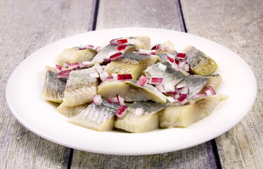 Mediterranean herring fillet served on a plate with chopped onion on the table