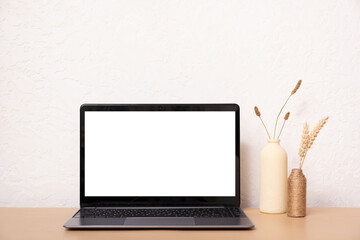 Laptop computer with blank screen, dried grass bouquet and vases. Aesthetic influencer boho styled interior design template with mockup laptop, copy space