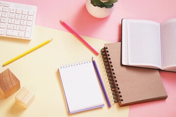 Modern workplace flat lay photography. Computer keyboard, paper notebook, coloured pencils on a table flat lay image