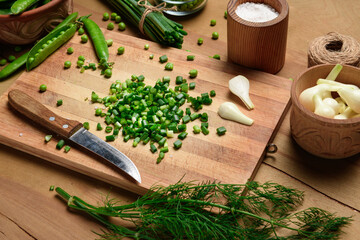 Fototapeta na wymiar vegetables on a wooden kitchen board, sliced green onions, dill and peas on a wood background, concept of fresh and healthy food, still life
