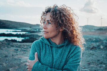 Concept of young woman and emotions. Inner balanced portrait of female enjoying freedom and sensations outdoor. Travel and wanderlust lifestyle people. Beautiul lady with curly long hair smiling - obrazy, fototapety, plakaty