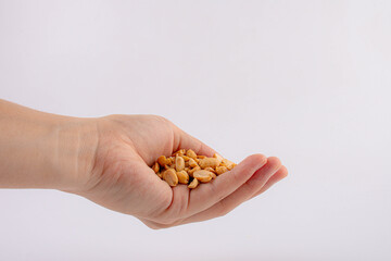 Fototapeta premium Hand holding heap of salt roasted peanuts on white background