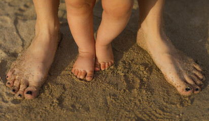 Fototapeta na wymiar Detail of Mother and baby legs and foot on the beach. 