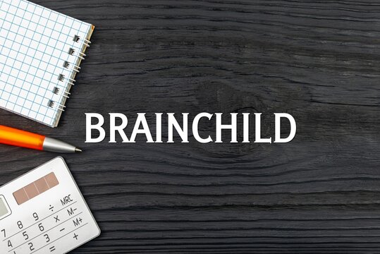 BRAINCHILD - word (text) on a dark wooden background, notepad. Business concept (copy space).