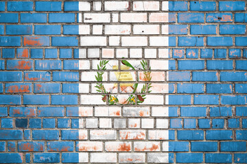 National  flag of the Guatemala  on a grunge brick background.
