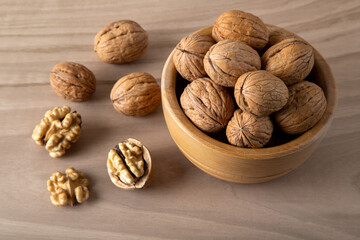 Bowl of walnuts and whole walnut kernels on wooden background,top view