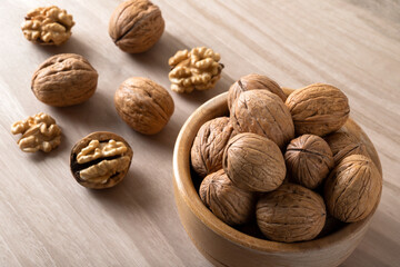 Bowl of walnuts and whole walnut kernels on wooden background,top view