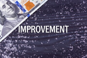 IMPROVEMENT - word (text) on a dark wooden background, money, dollars and snow. Business concept (copy space).