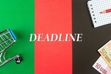 DEADLINE - word (text) and euro money on a table of different colors, a trolley, a basket of grocery notepad and a red pencil. Business concept, buying, selling, supermarket, store (copy space).
