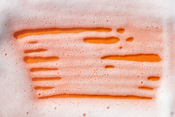 Foam on an orange background. Soapy liquid texture with bubbles. Natural sunshine and shadows....