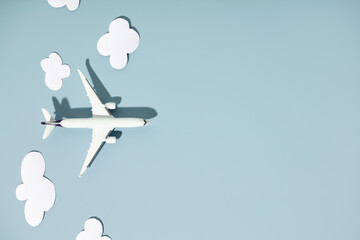 Miniature toy airplane and paper clouds on colorful background. Flat lay design of travel concept