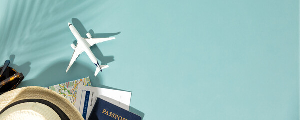 Miniature toy airplane, travel accessories and paper clouds on colorful background. Flat lay design...