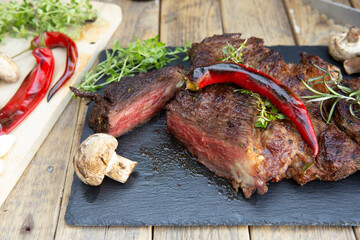 Grilled beef steak on wooden table top. Healthy food concept. Beef cut outdoors, garden kitchen, bbq grill patio