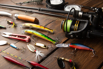 Fishing tackle - fishing spinning rod, hooks and lures on wooden background. Active hobby...