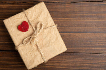 Valentine's Day greetings concept. Little red wooden crafted heart and gift box close up on the wooden background. Valentines greeting card.
