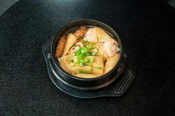Korean Odeng Tang/Eomuk/Odeng Guk, Korean fish cake soup in traditional pot on black table background