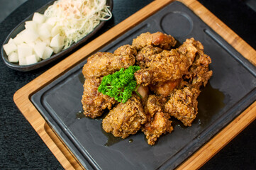 Korean Fried Chicken with Honey Garlic sauce, traditional Korean fried chicken on grill plate with pickle dishes on black table background
