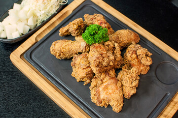 Korean Fried Chicken Original, traditional Korean fried chicken on grill plate with pickle dishes on black table background