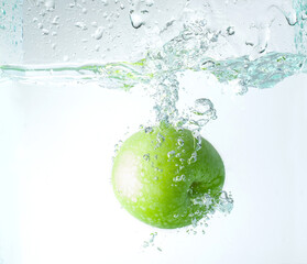 Fresh apples falling into water with splashes, copy space for text.