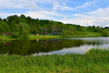 Fototapeta premium A view from the top of a tall hill or mountain with vast fields, meadows, forests, moors, and other types of flora visible, with a lake, some urban settlements, and other buildings in the distance