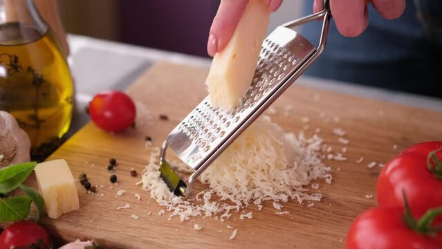 making pasta carbonara - grating parmesan cheese on wooden cutting board
