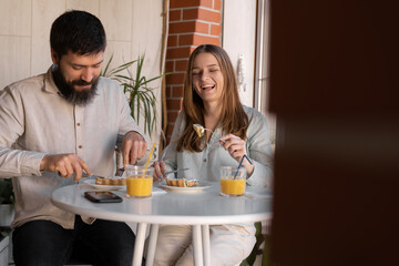 Obraz na płótnie Canvas Happy young couple enjoying their breakfast together