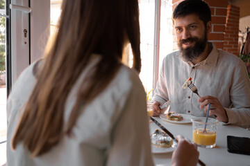 Happy loving couple enjoying breakfast in a cafe. Love, dating, food, lifestyle