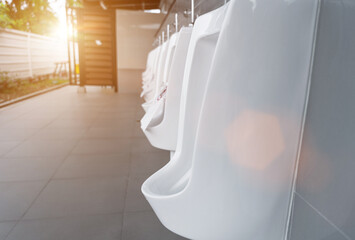 Closeup of white urinals in men's bathroom. Ceramic urinals in public male toilet. washroom,...