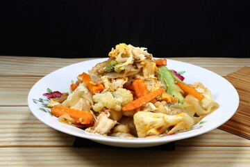 Traditional fried rice noodle mixed with fresh vegetable serving on the plate. Famous street food menu in Asia.