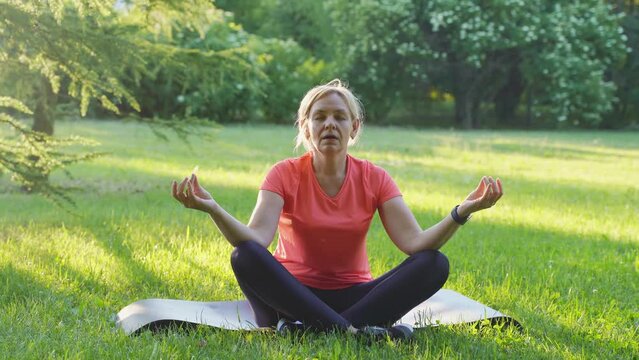 Mature woman meditate outdoors in a park on sunset with running child. mindful mother sport activity 
