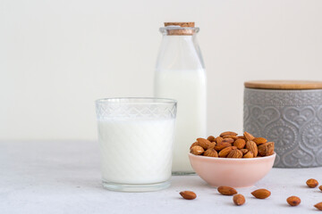 Almond milk in the glass with almond in the wooden bowl on the wooden table.