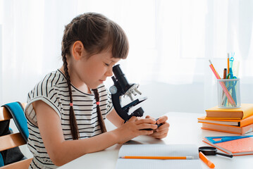 School girl with microscope for school education at home