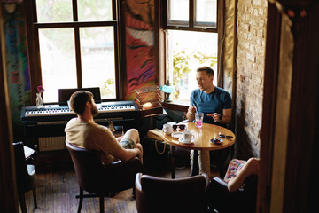 Fototapeta na wymiar Two adult male friends sitting and talking in cafe.
