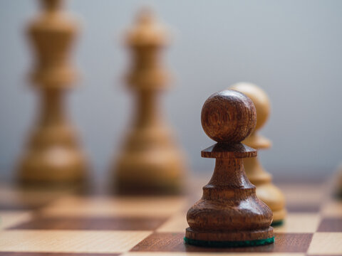 Wooden chess pawn with King and Queen desfocused. Intellectual fight concept