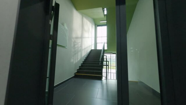 Spacious hallway with wooden shelving and open doors to empty staircases in new school building first point view