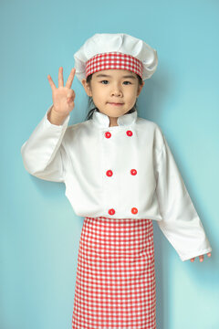 Little Asian Girls In Chef Uniform With Okie Pose.