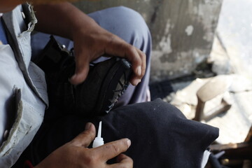 Repairing broken shoes by a shoe repairman. Loose leather shoe soles are being reattached with strong glue. Isolated on a shoe repairman manually. 