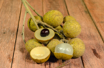 bunch of longan peel show the white meat with black seed place on a wooden background