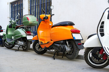Many mopeds and scooter motorcycles parked in the street
