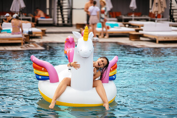 Woman on inflatable unicorn toy mattress float in pool. - 518058304